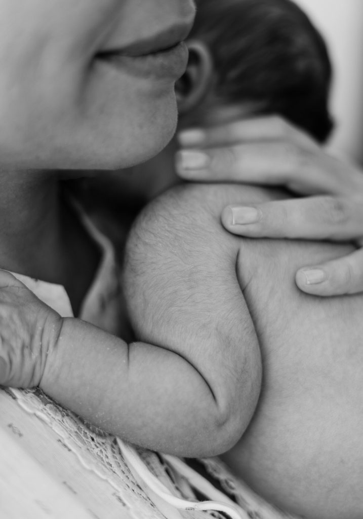 Close-up black and white image of a mother holding her newborn baby, showcasing love and bonding.