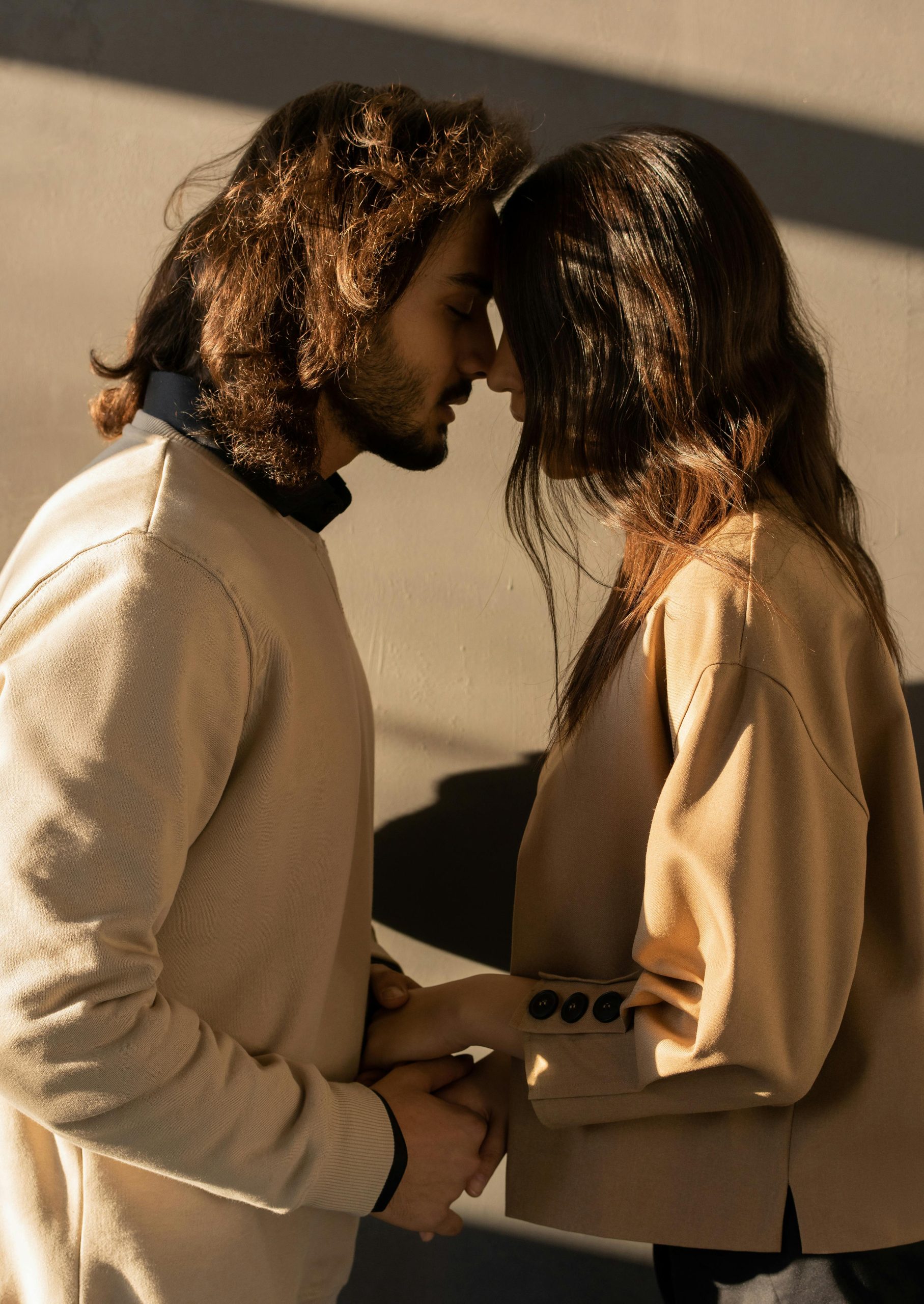 A tender moment between a couple in love, embracing indoors with sunlight casting shadows.