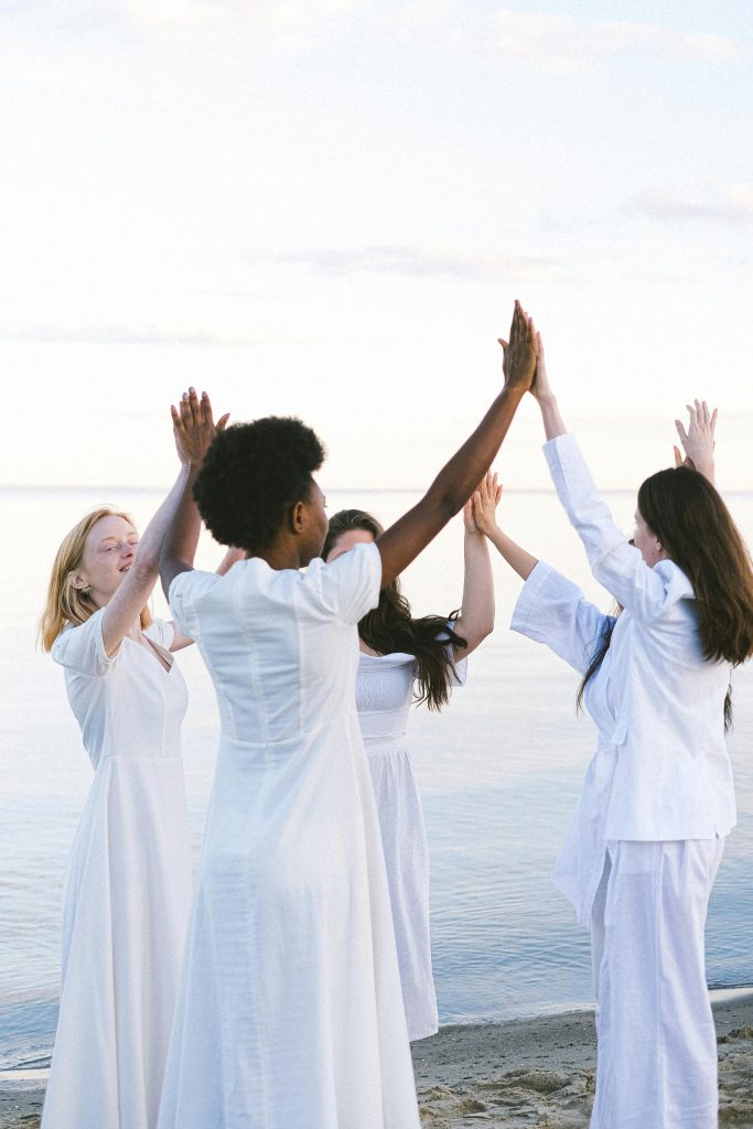 Group of women in white dresses enjoying a joyful moment by the seaside.
