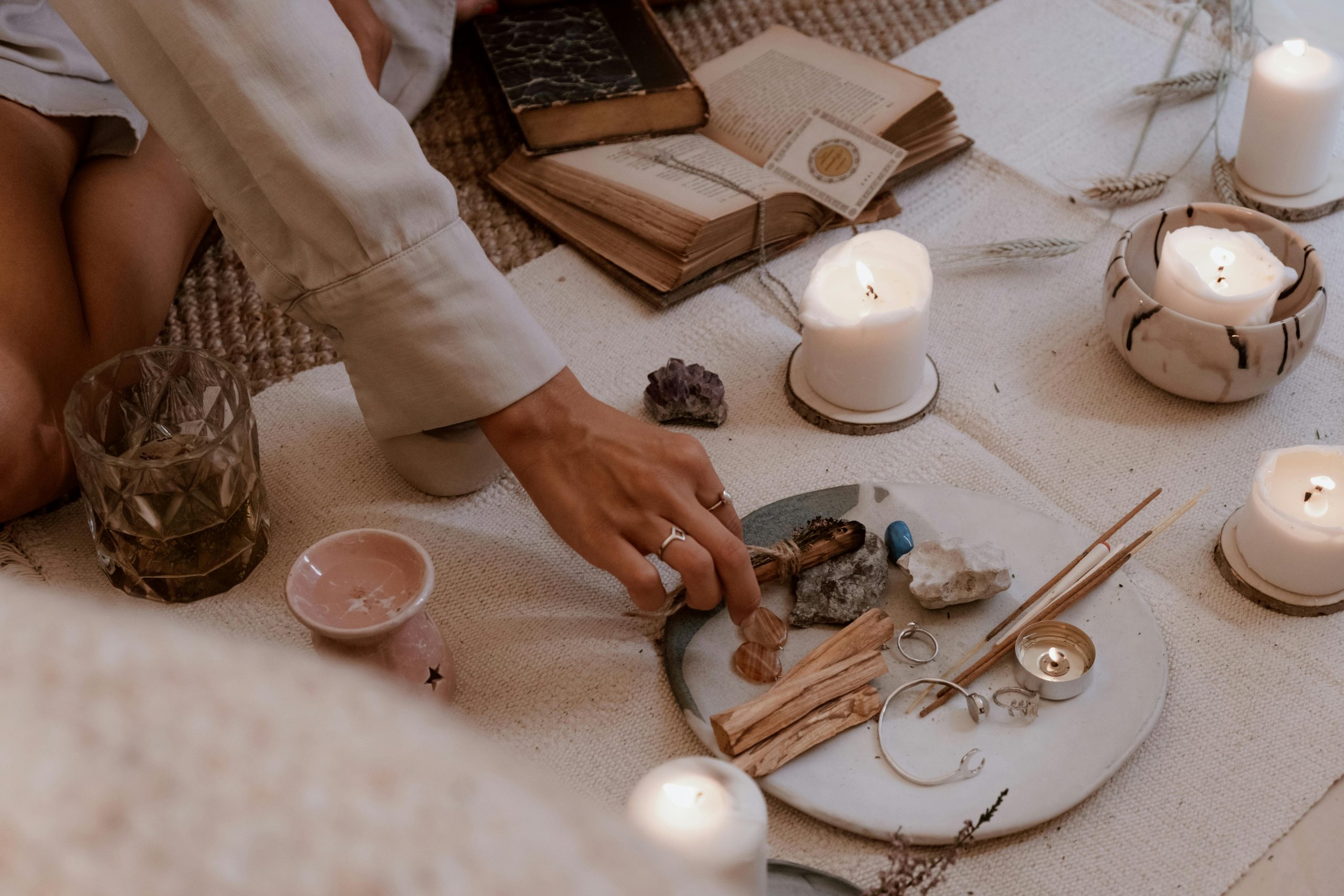 A peaceful ritual scene with candles, crystals, and incense sticks on a wooden table.