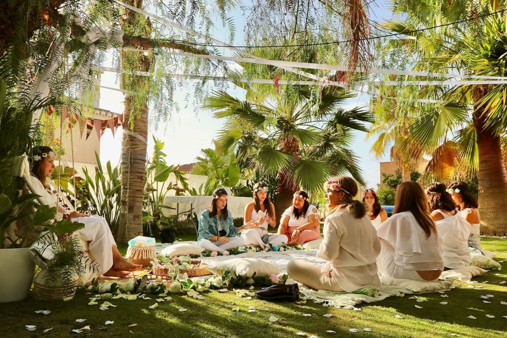 a group of women sitting on top of a lush green field
